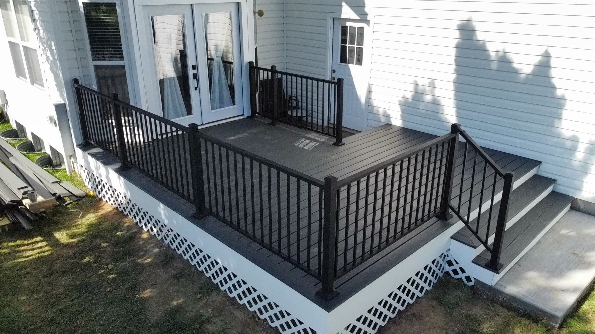 Picture-frame composite deck with aluminum rails and lattice skirting, replacing a rotted wood deck
