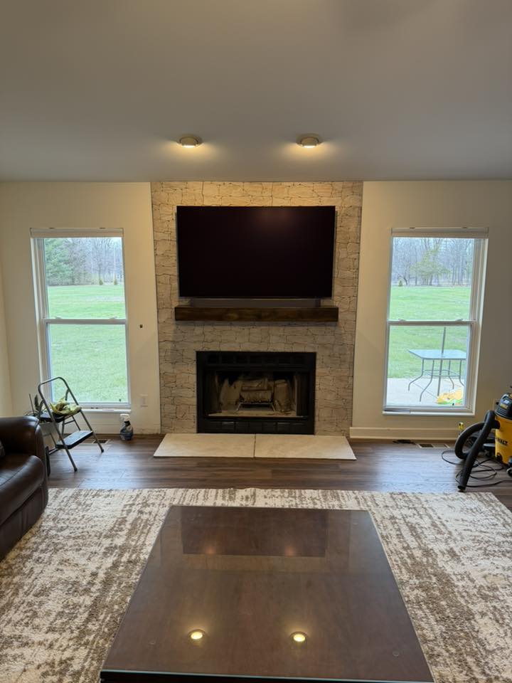 Stone fireplace with hand-built custom mantel hiding coax, power, and Ethernet cabling for a soundbar