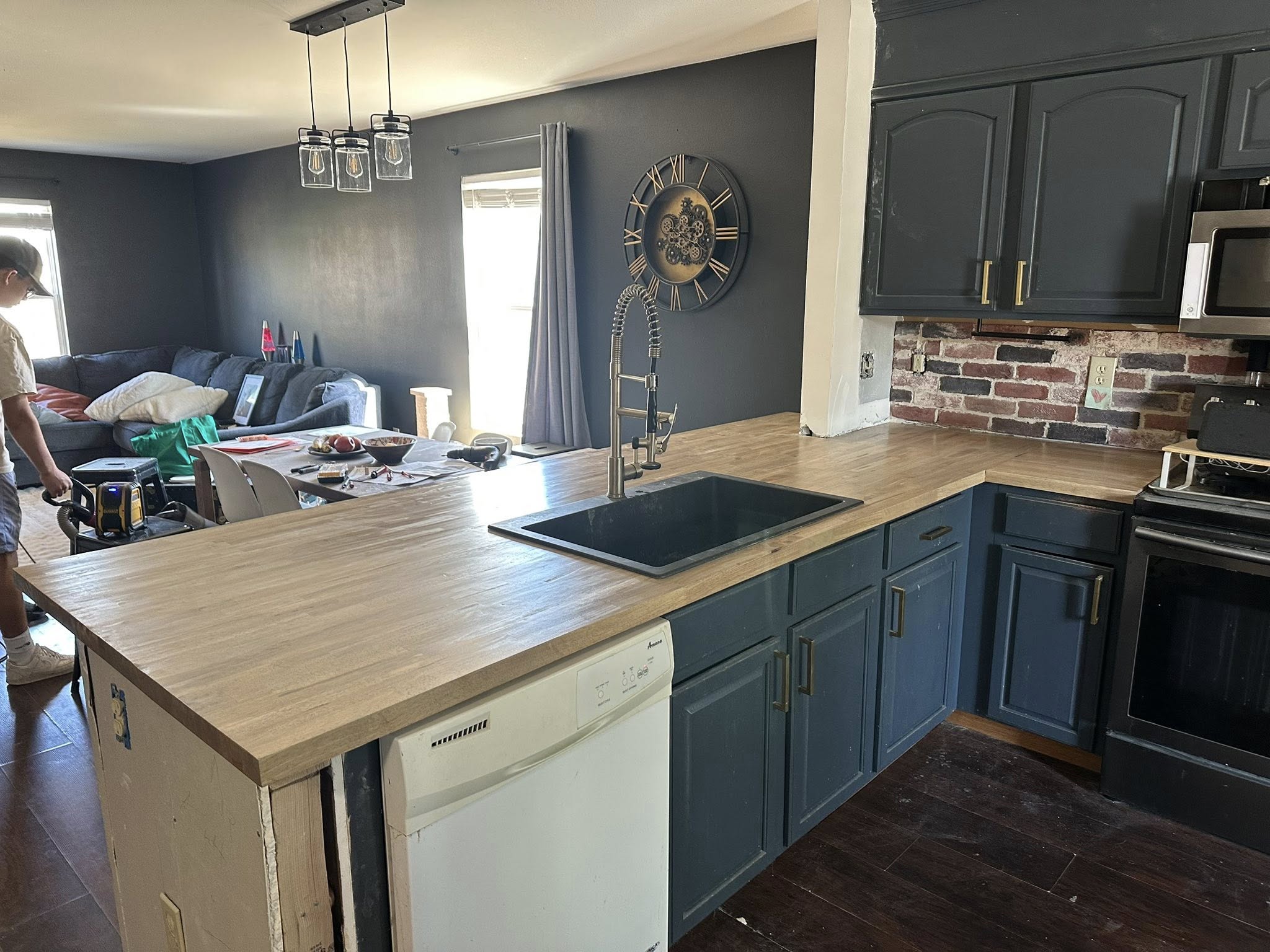 Open-layout kitchen with custom hevea butcher-block counter and brick backsplash after wall removal