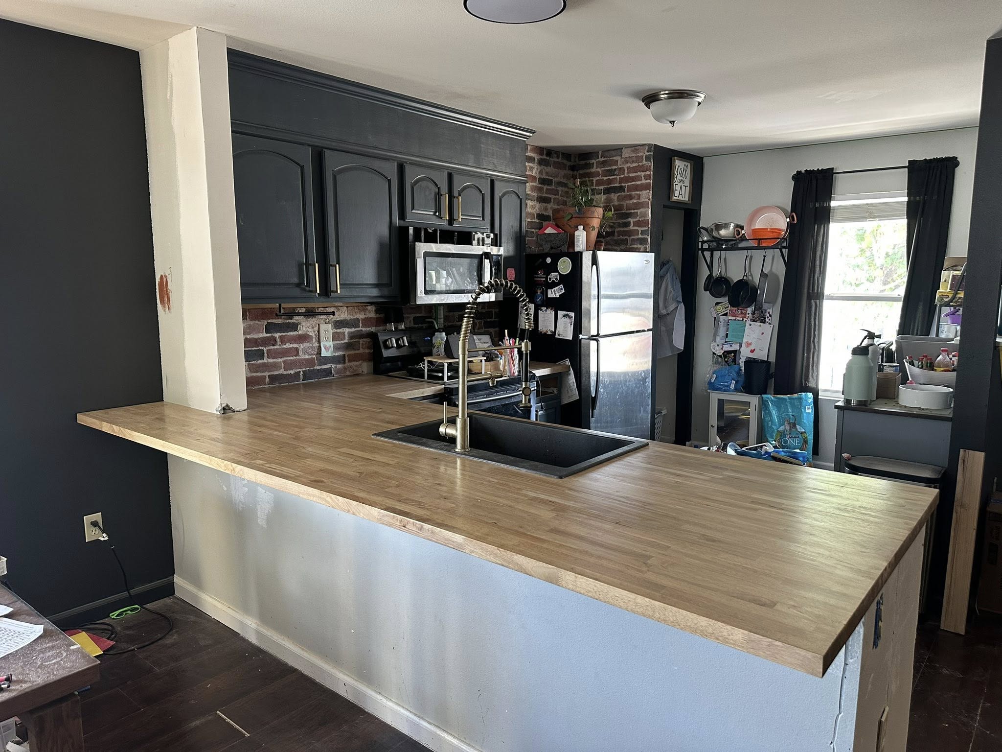 Hevea butcher-block counter in weather-oak finish, wrapping around the removed wall